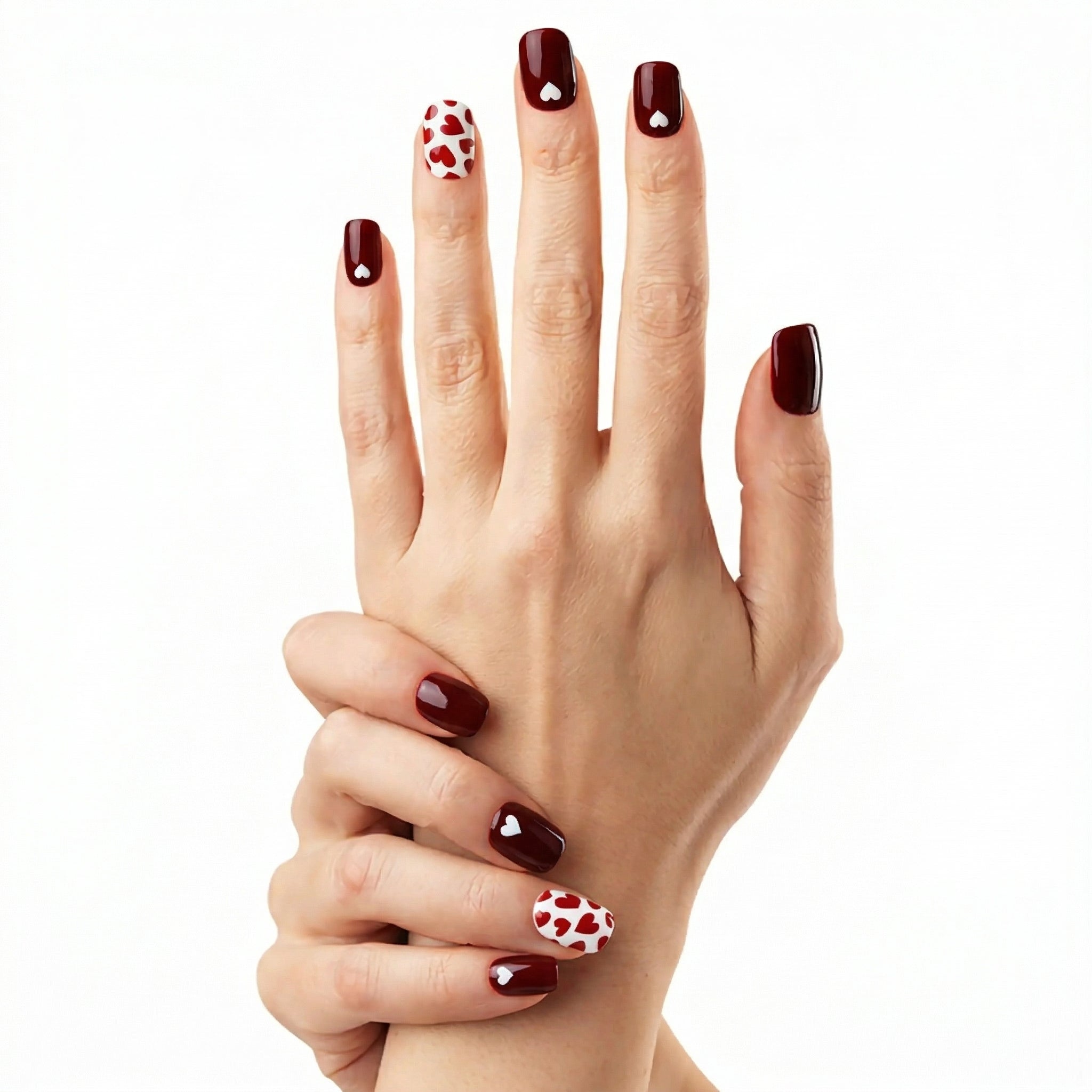 Main croisée avec ongles courts rouge bordeaux et motifs cœurs blancs Glamisu, manucure romantique naturelle sans UV