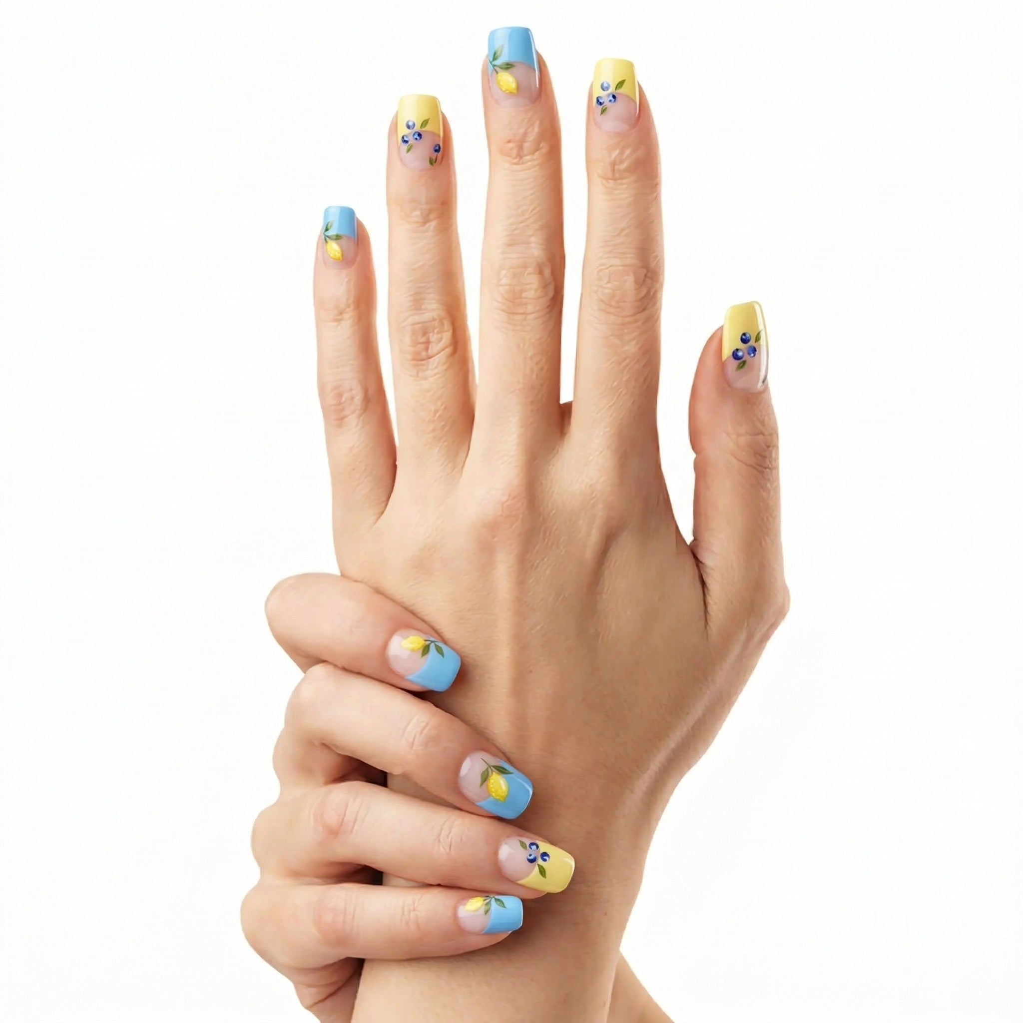 Duo de mains avec ongles pastel bleu et jaune citron Glamisu ornés de fleurs et fruits, manucure estivale fraîche sans UV